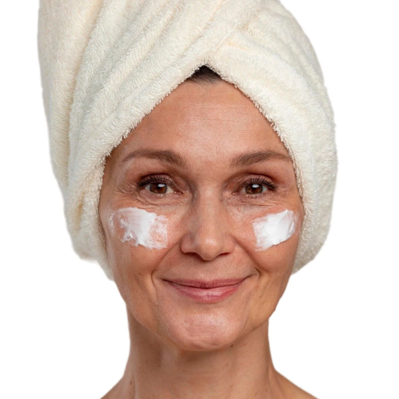 White woman in white head towel with face cream on cheeks. Best anti-aging cream for face. Dermal Essentials Medical Grade Skincare.