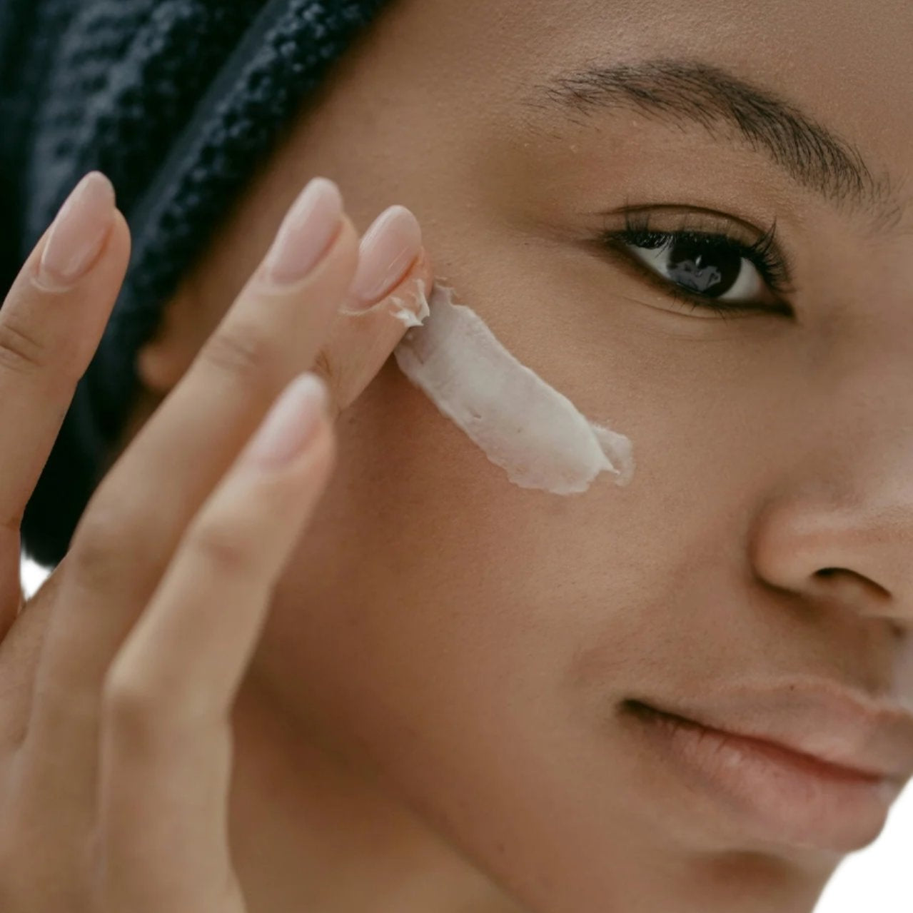 black woman black hair braids brown eyes applying best anti-aging white face cream.
dermal essentials clinical grade skincare