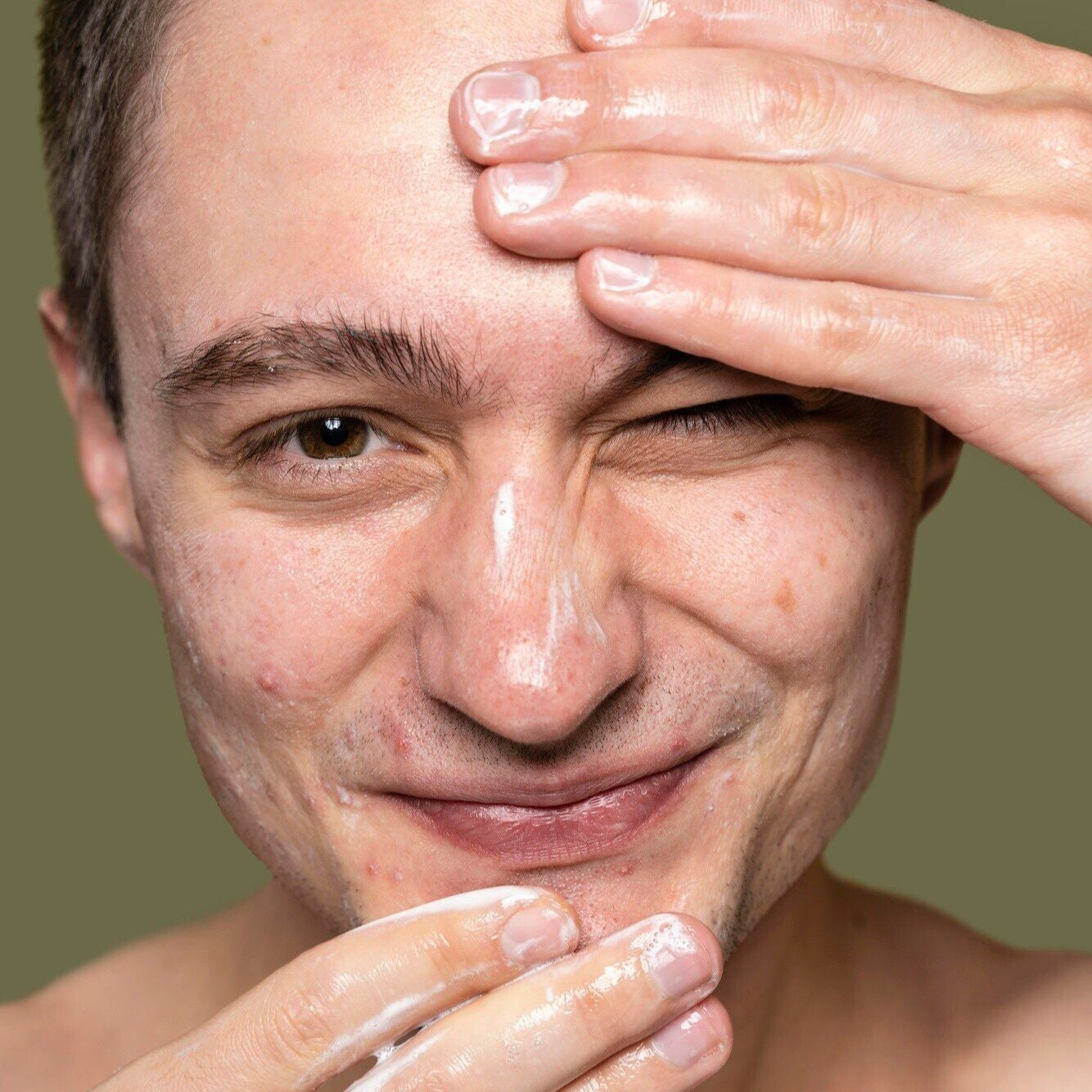 white young man brown hair applying facial cleanser dermal essentials medical grade skincare