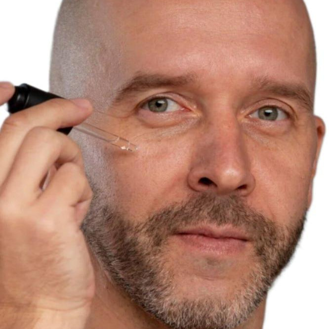 White bald man with beard using black dropper to apply best skin plumping serum. Dermal Essentials Medical Grade Skincare.