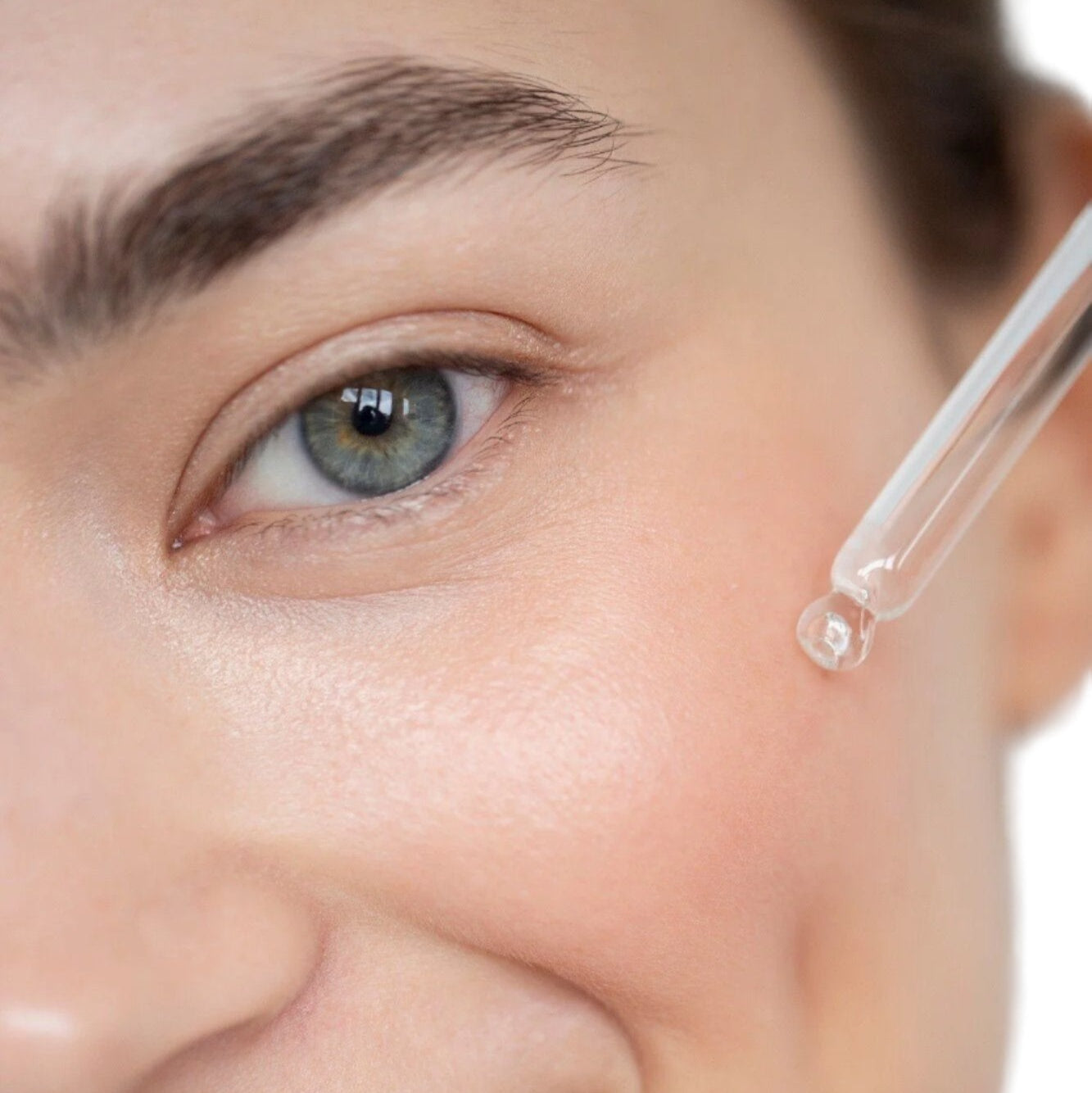 White woman brown hair blue eyes using dropper to apply best skin plumping serum. Dermal Essentials Medical Grade Skincare.