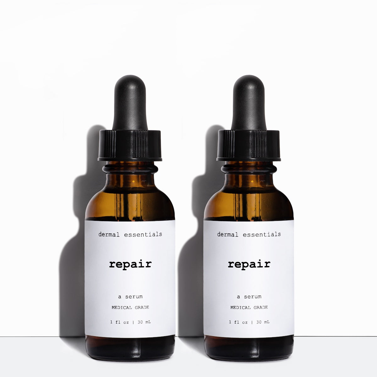 Two Amber cylinder glass jars black eye dropper white label black letters 1 fl. oZ. Best vitamin C serum with Vitamin E and ferulic acid. Dermal Essentials Medical Grade Skincare.
