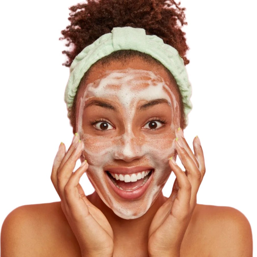 Black woman green headband applying best facial cleanser. Dermal Essentials Medical Grade Skincare.