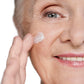 Mature white woman grey hair applying hydrating, nourishing face mask.  Dermal essentials medical grade skincare.