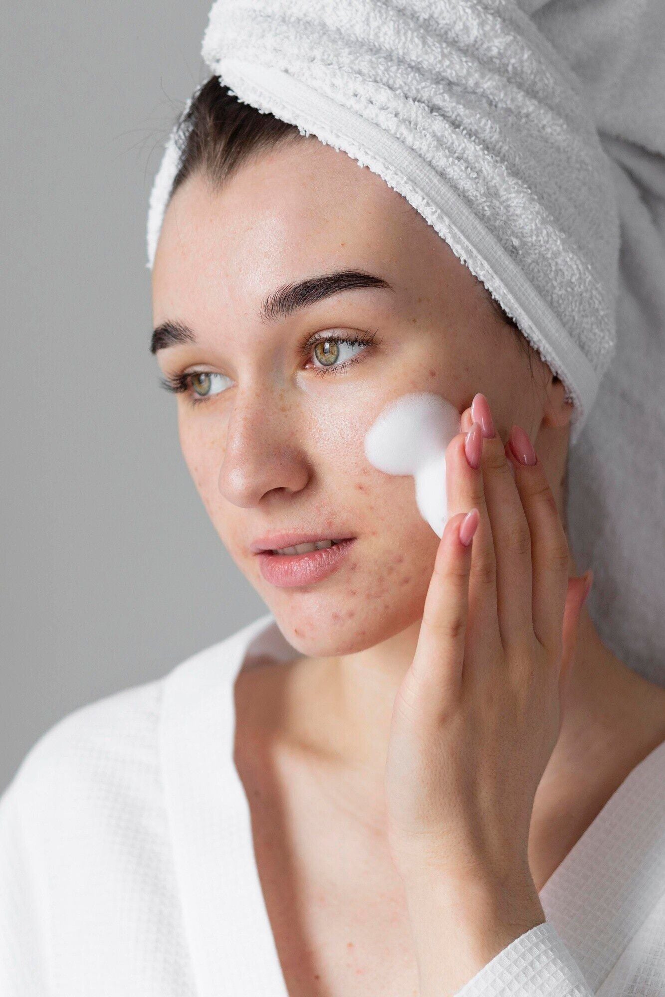 white woman white head towel white hand applying white acne cleanser dermal essentials medical grade skincare