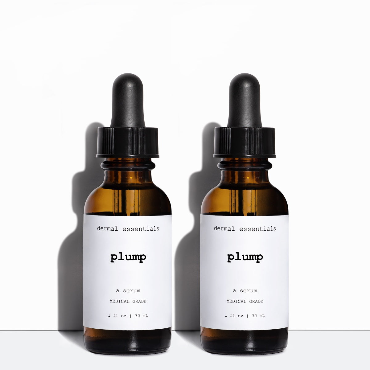 Two amber cylinder glass bottles white label black letters black eye dropper 1 fl. oz. Best skin plumping serum. Dermal Essentials Medical Grade Skincare.  